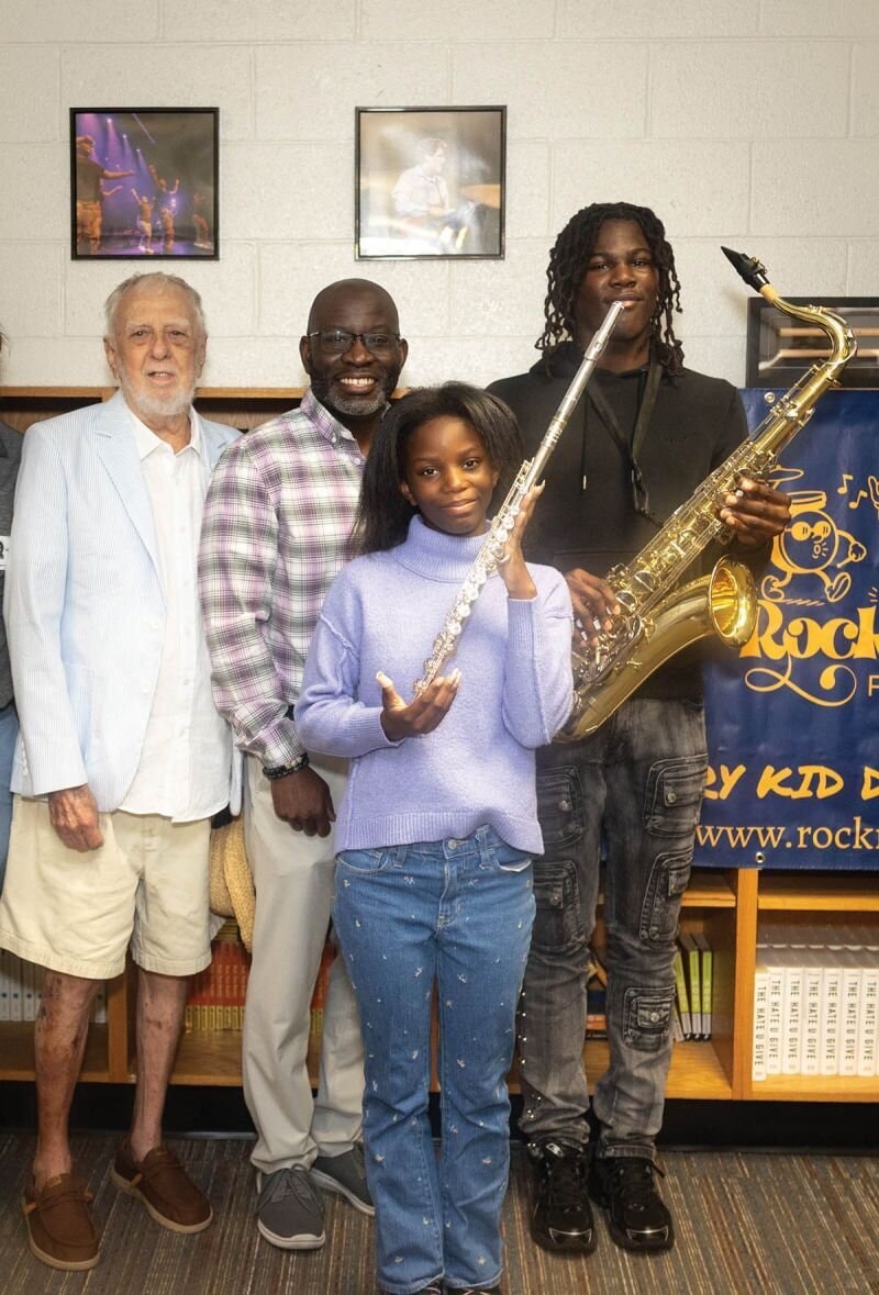 Young musicians holding flute and saxophone at a Rock N Roll Rescue donation event